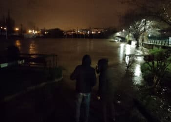 Dos viandantes observando esta pasada noche el campo de rugby de Hernani de nuevo inundado. Foto: Santiago Farizano