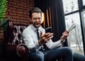 handsome businessman with candid emotions holding his smartphone and newspaper while sitting on armchair 120x86 - Bwin apuestas: Por qué unirse a esta casa de apuestas